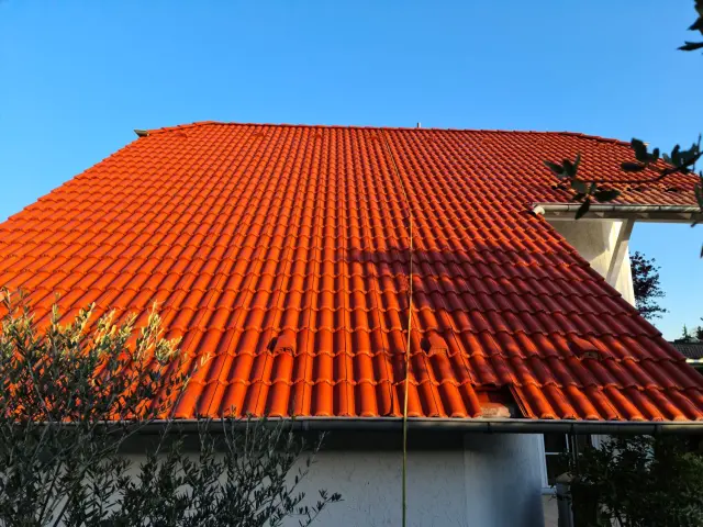 Frisch gereinigtes und beschichtetes Ziegeldach in einheitlichem Rot mit glatter, geschützter Oberfläche.