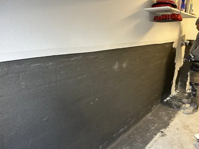 Kellerwand mit schwarzer Abdichtung zur Kellertrockenlegung und Feuchtigkeitssanierung durch MK Bauspezialist.
