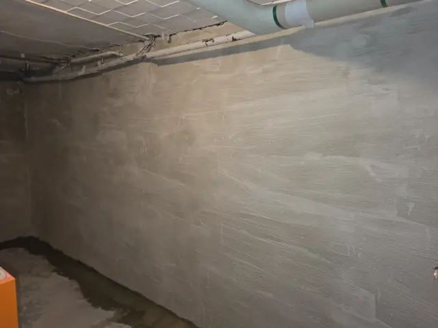 Sanierte Kellerwand mit neu aufgetragenem Putz zur Behandlung von Feuchtigkeit und Schimmelproblemen.
