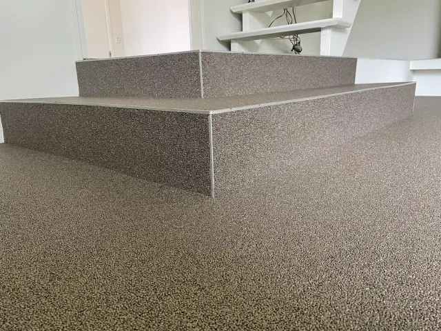 Fugenloser Steinteppich im Innenbereich auf Podest und Treppe mit moderner, robuster Oberfläche.